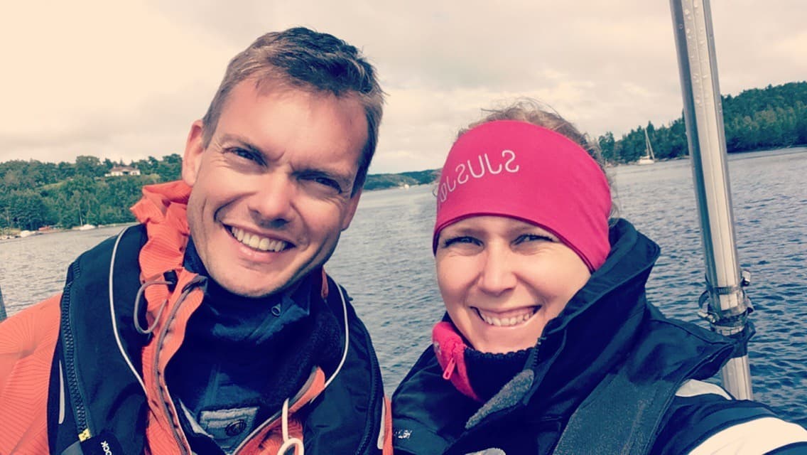 Grethe og Marius smiler om bord i en seilbåt på sjøen, iført redningsvester.